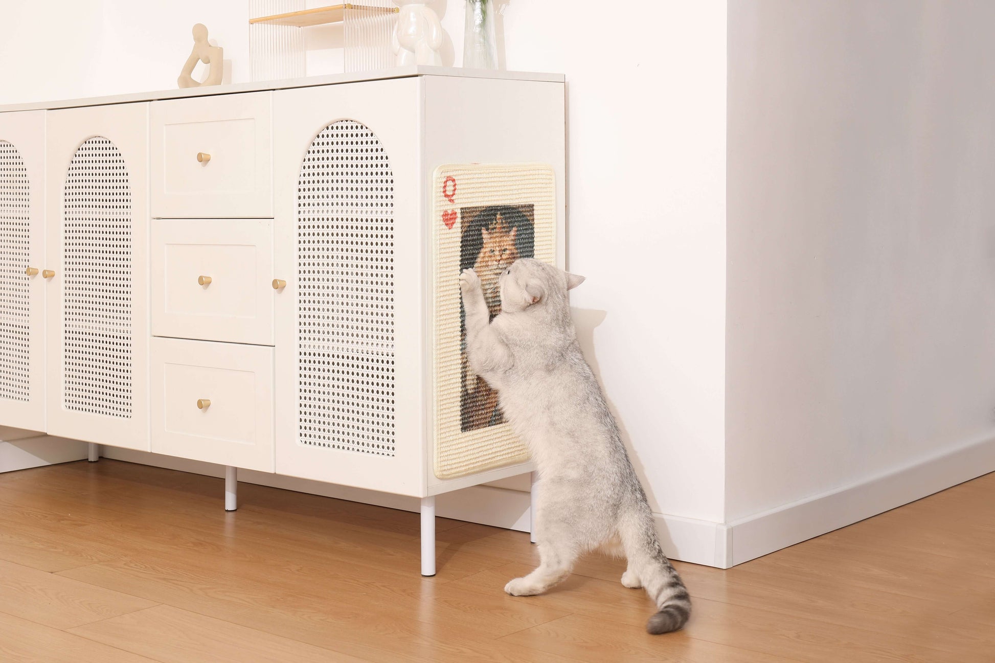 Cat using an art-inspired natural sisal scratching mat against a stylish cabinet in a modern home.