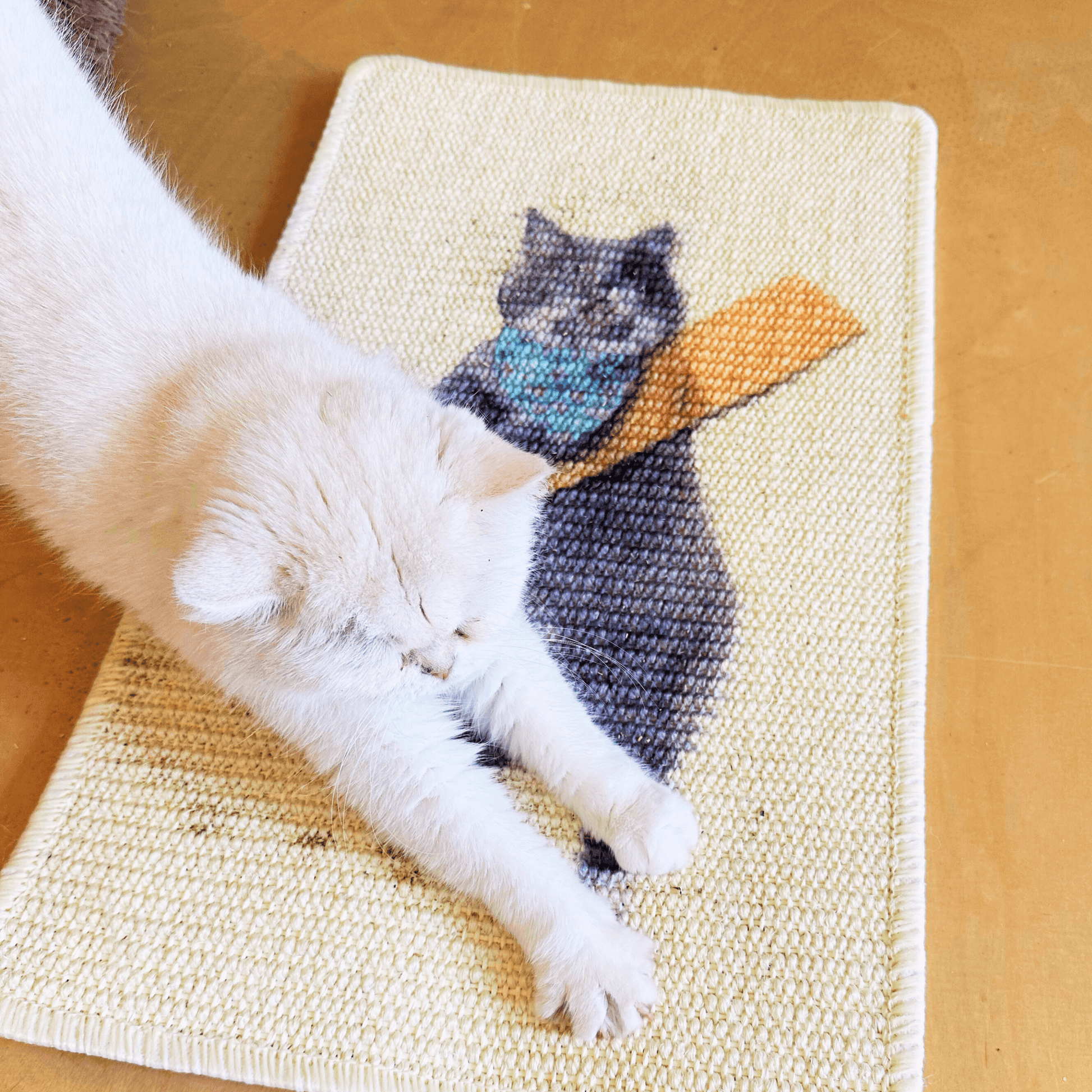 Cat stretching on art-inspired natural sisal scratching mat with playful design.