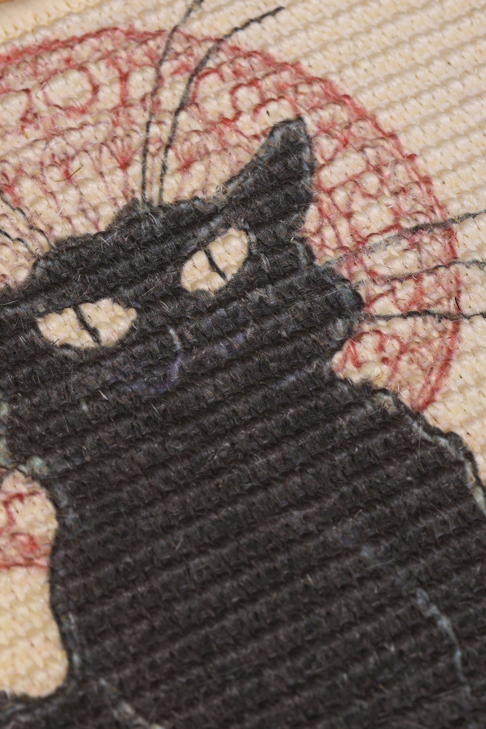 Close-up of a black cat design woven into a natural sisal scratching mat, ideal for feline scratching and play.