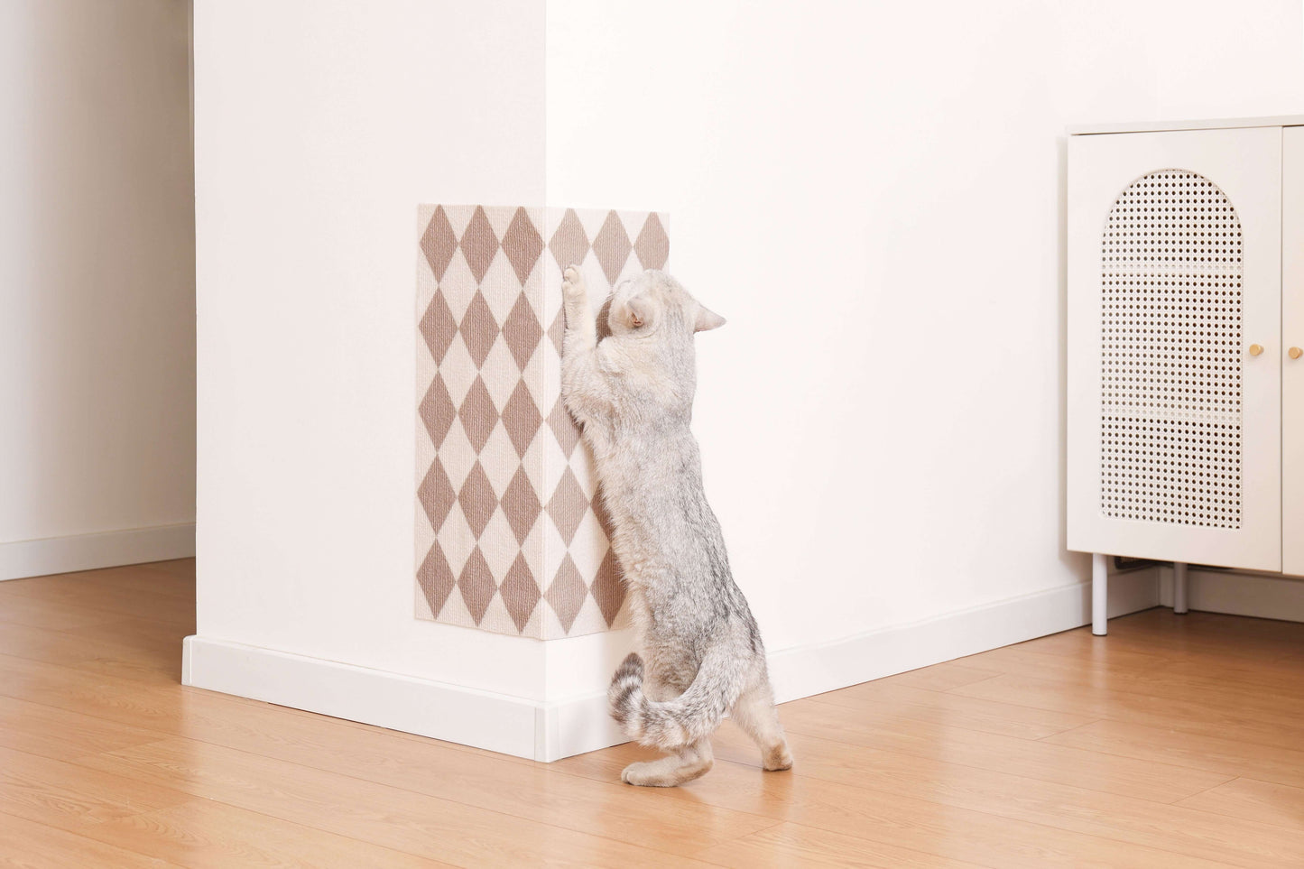 Cat using stylish patterned scratching mat on wall, blending with home decor, featuring trimmable design and strong self-adhesive backing.