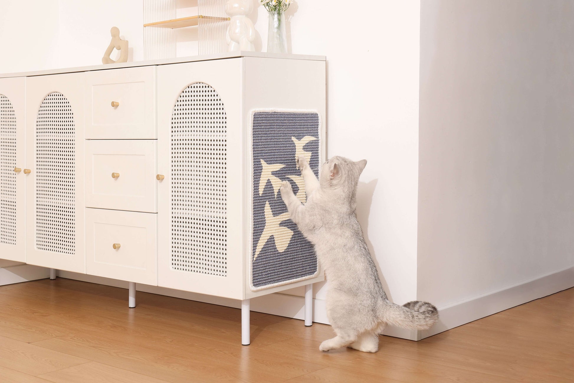 Cat using an art-inspired sisal scratching mat on a modern cabinet, promoting safe scratching and play.