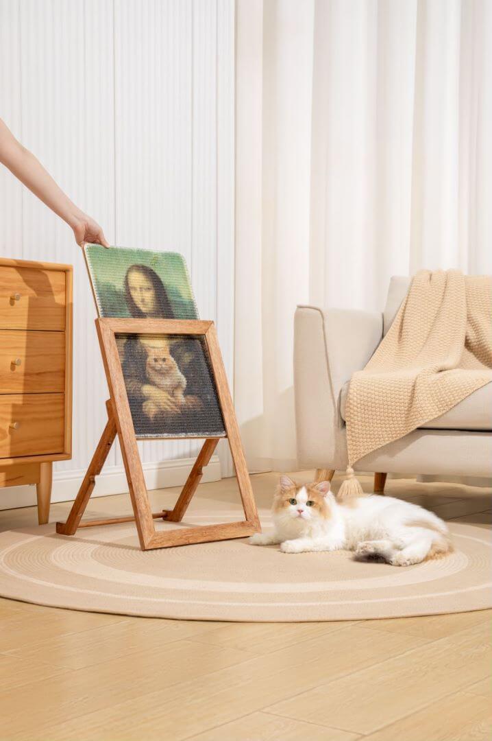 Cat enjoying the Ultimate Art Scratcher beside an art frame in a cozy living room setting.