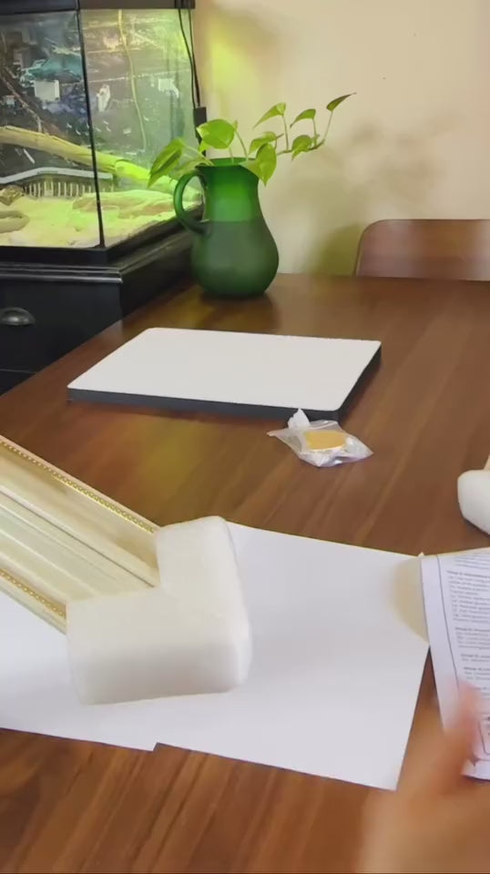 Workspace featuring a green plant, art supplies, and a whiteboard on a wooden table.