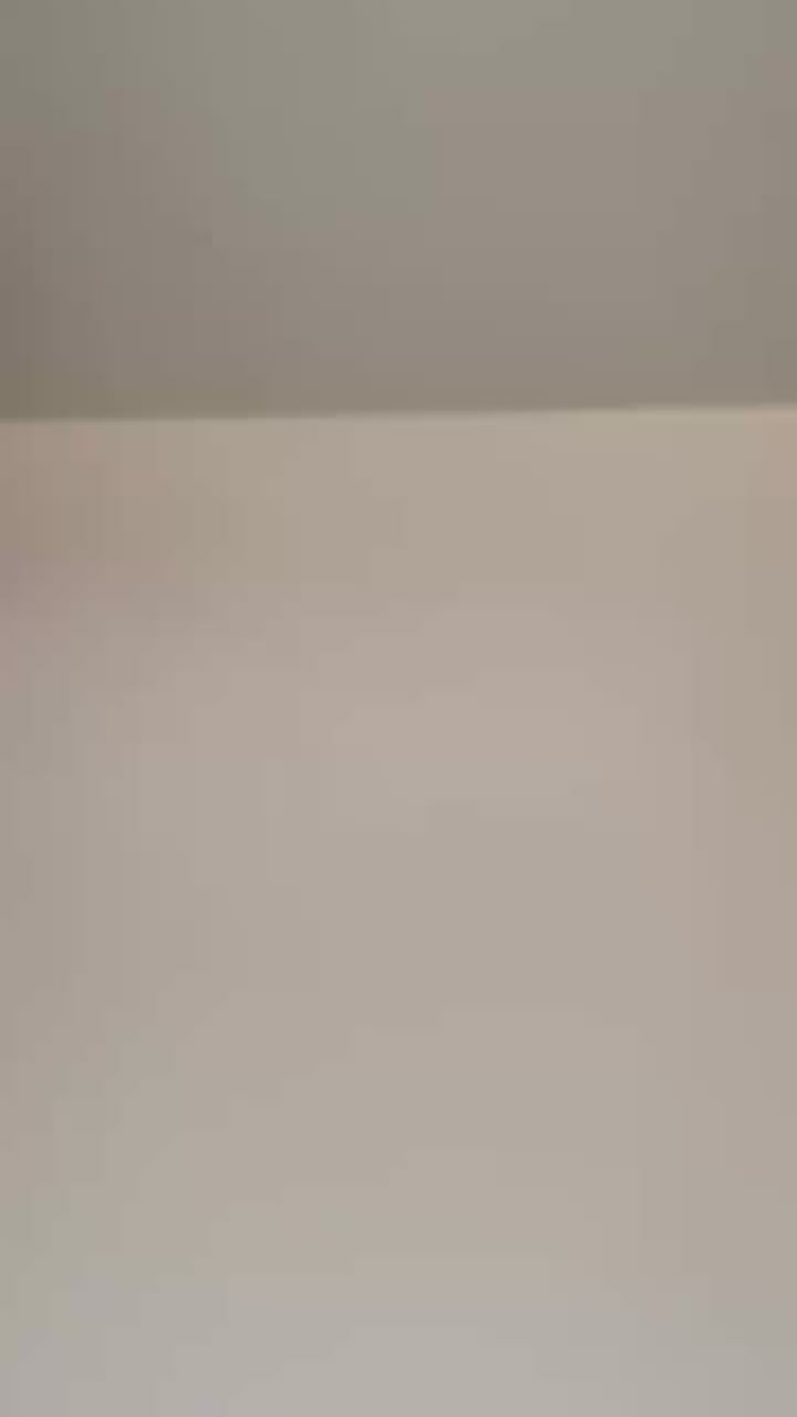 Close-up view of a plain white wall with a light-colored ceiling.